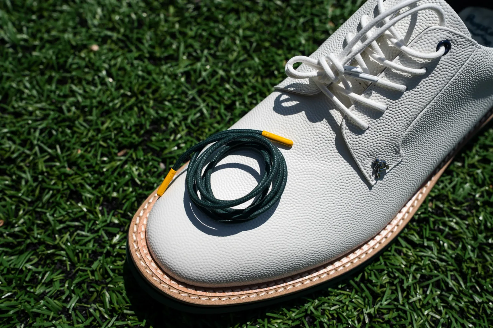 Close-up of the white leather shoe with the spare green lace