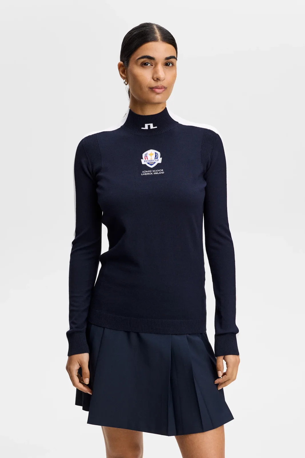 Woman in the navy Adia knit sweater with white intarsia sleeves and a pleated skirt