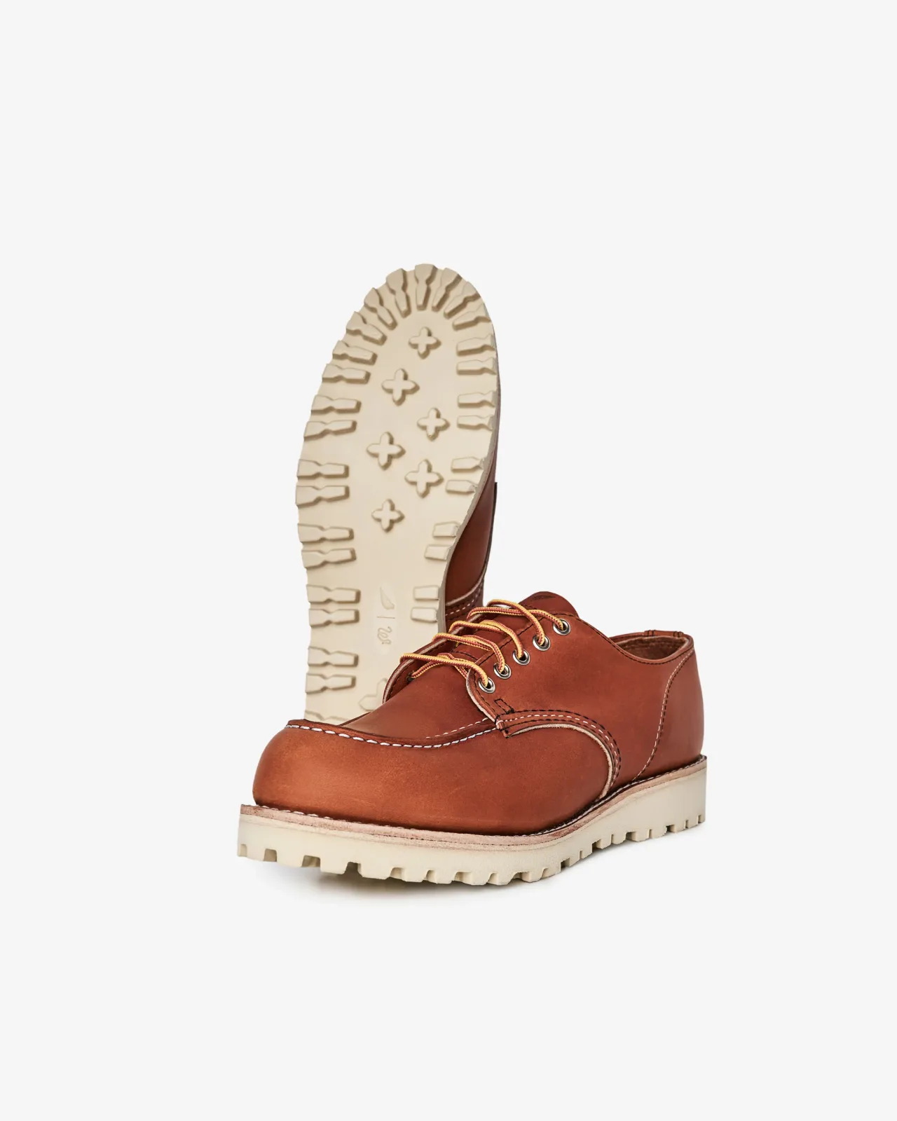 Pair of brown leather moc-toe oxfords, one showing the cream wedge sole